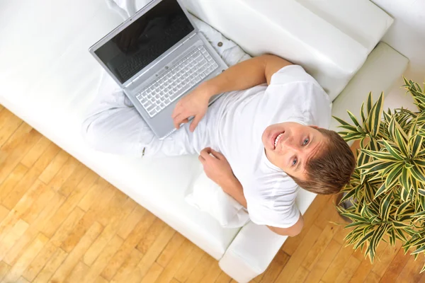 Φοιτητής χαλαρωτικό με το laptop του σε έναν καναπέ — Φωτογραφία Αρχείου