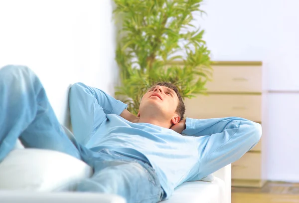 Lunghezza completa di un giovane ragazzo che si rilassa sul divano in casa — Foto Stock