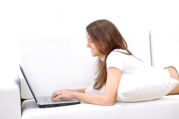 Lachende vrouw liggend op de Bank met laptop. — Stockfoto