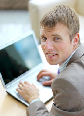 Businessman sitting at desk in office, working with laptop computer, lookin clipart