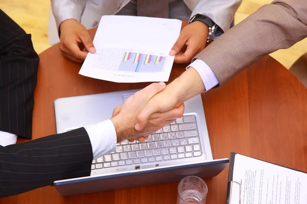 stock image Handshake over paper and pen,blurry computer in the background