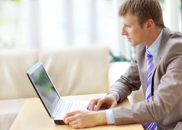 Homme d'affaires assis au bureau, travaillant avec un ordinateur portable, regardant — Photo