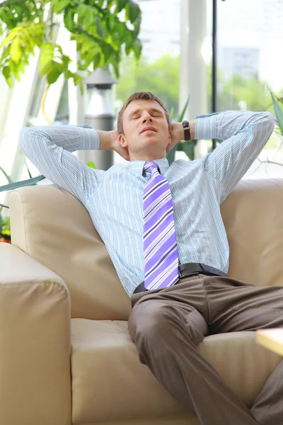 Jeune homme d'affaires détendu avec les mains derrière la tête au travail — Photo