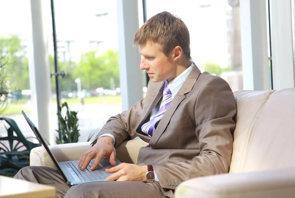Businessman working on laptop computer at office lobby — Stock Photo, Image