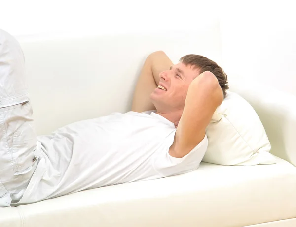 Longitud completa de un joven que se relaja en el sofá en casa — Foto de Stock