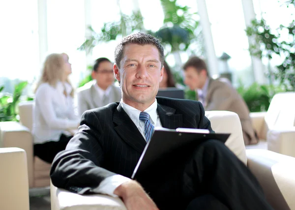 Glad affärsman med kollegor på en konferens i bakgrunden — Stockfoto