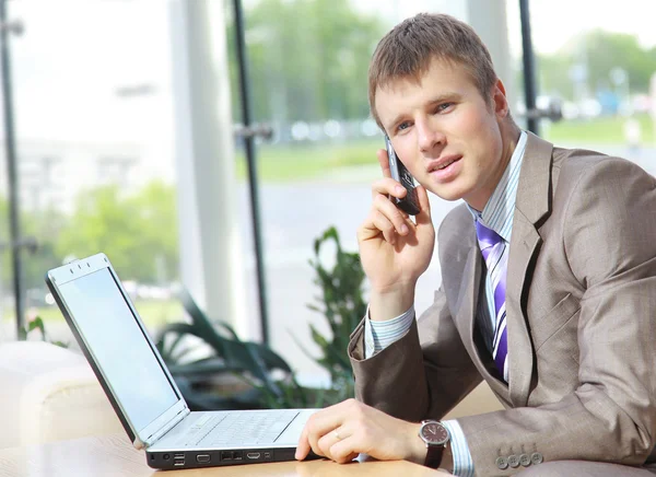Biznes przystojny facet pracuje na telefon i laptop razem, gdy w wor — Zdjęcie stockowe