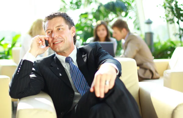 Geschäftsmann auf Abruf, Mitarbeiter reden im Hintergrund — Stockfoto