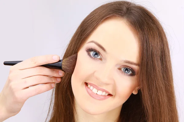 Retrato de una joven atractiva aplicando colorete — Foto de Stock