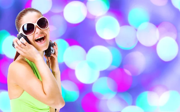 Жінка в зеленій сорочці і сонцезахисних окулярах слухає музику за допомогою фонової служби — стокове фото