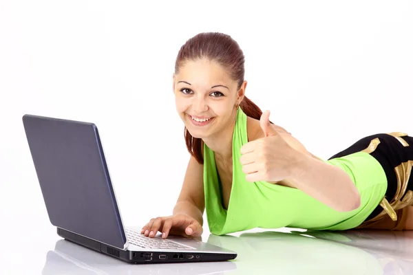 Portrait of a young girl sitting on sofa with a laptop and showing thumbs u — Stock Photo, Image