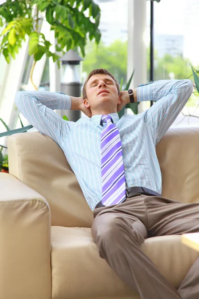 Junger entspannter Geschäftsmann mit den Händen hinter dem Kopf bei der Arbeit — Stockfoto