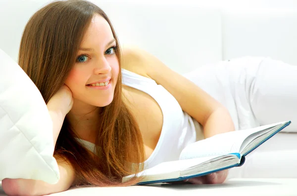 Volledige lengte van een jonge dame liggend op de Bank lezen van boek — Stockfoto