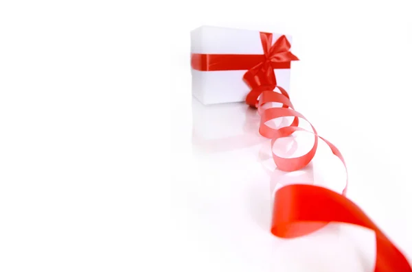 Cadeau enveloppé avec un ruban rouge sur un fond blanc — Photo