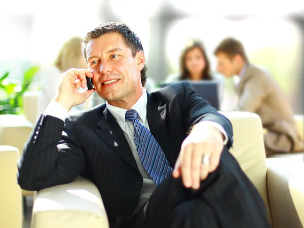 Üzletember koncentrálva hívás, háttérben a munkatársak talkling — Stock Fotó