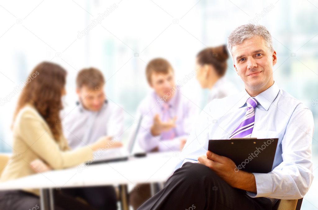Portrait of a senior business man attending a conference with the rest of h