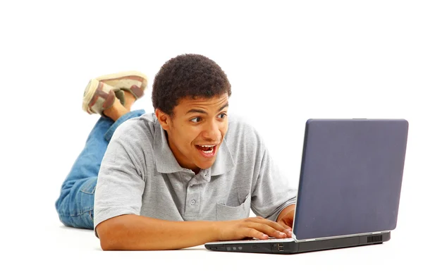 Gelukkig jonge man aan het werk op een laptop, geïsoleerd tegen witte achtergrond — Stockfoto