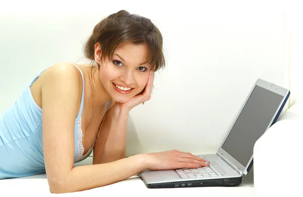 Gülümseyen kadın kanepede dizüstü bilgisayar ile yalan söylüyor.. — Stok fotoğraf