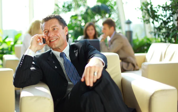 Homem de negócios falando no celular em uma reunião — Fotografia de Stock