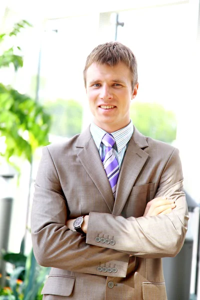 Happy businessman standing with hands in pocket in front of windows, lookin — Stock Photo, Image