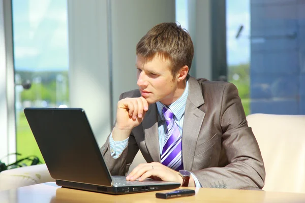 Бизнесмен, работающий за ноутбуком в офисном холле — стоковое фото