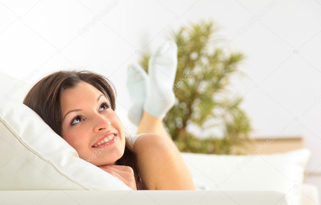 Smiling girl lying down on divan and thinking