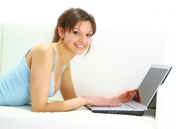 휴대용 퍼스널 컴퓨터와 소파에 누워 웃는 여자. — 스톡 사진
