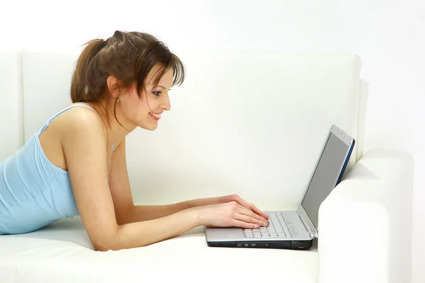 Lachende vrouw liggend op de Bank met laptop. — Stockfoto