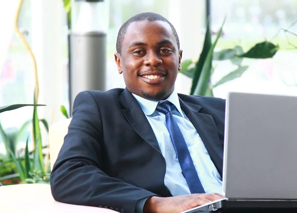 Portret van een knappe jonge zakenman met een laptop — Stockfoto