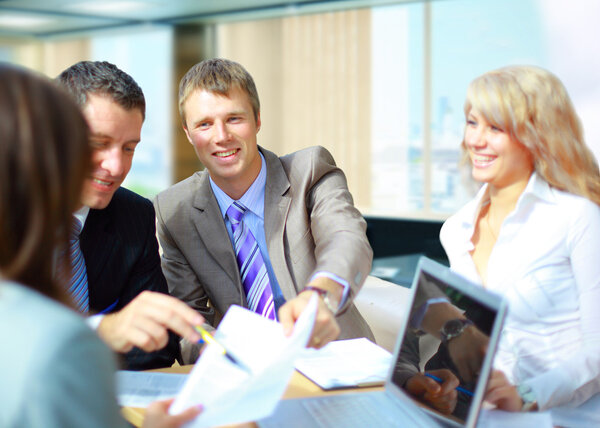Успешная бизнес-команда с документом на столе с ноутбуком
