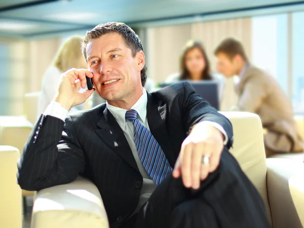 商务男人手机虽然在一次会议上发言 — 图库照片