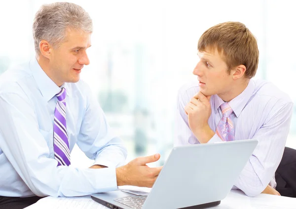 Dos hombres de negocios mirando un portátil en la oficina —  Fotos de Stock