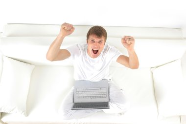 rahatlatıcı bir dizüstü bilgisayar kullanırken koltukta genç bir adam portresi