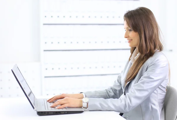 Attrayant souriant jeune femme d'affaires en utilisant un ordinateur portable au bureau — Photo