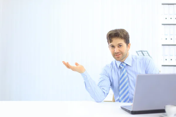 Uomo d'affari giovane e sicuro di sé con un computer portatile in ufficio — Foto Stock