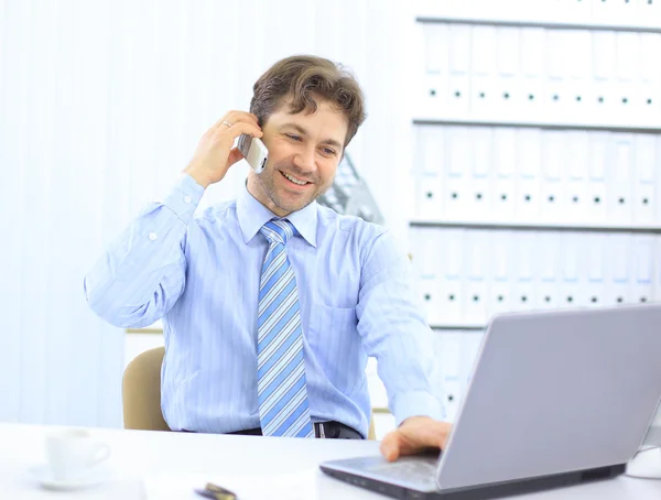 Handsome business guy working on cellphone and laptop together while at wor — Stock Photo, Image
