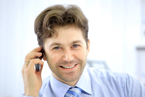 Handsome business guy working on cellphone and laptop together while at wor — Stock Photo, Image