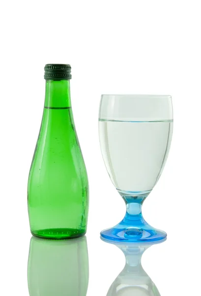 Bottle and glass of mineral water reflected on w — Stock Photo, Image