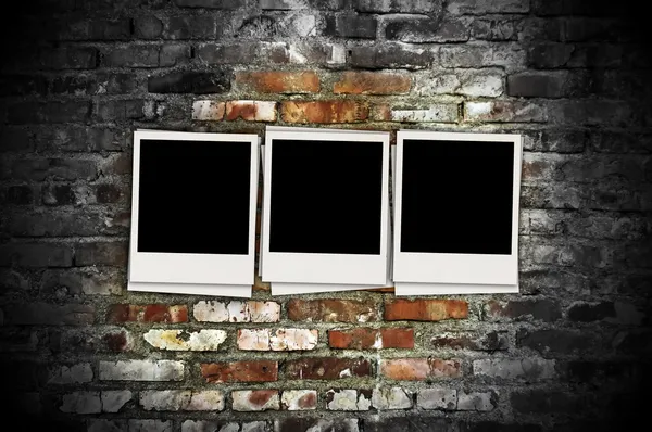 Três fotos em branco no fundo do tijolo — Fotografia de Stock
