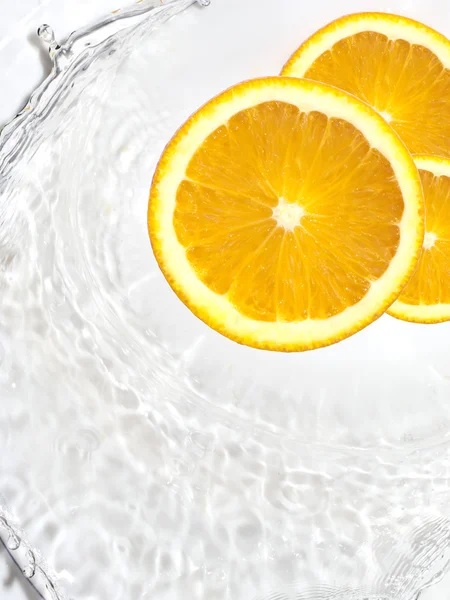 Oranje segmenten in water spatten — Stockfoto