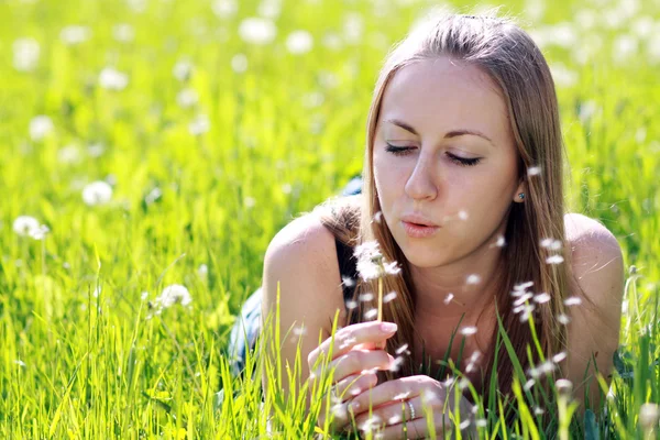 Girl blows on a dandelion — Stock Photo, Image