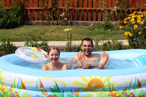 Młode pary kąpie się w basenie nadmuchiwane — Zdjęcie stockowe