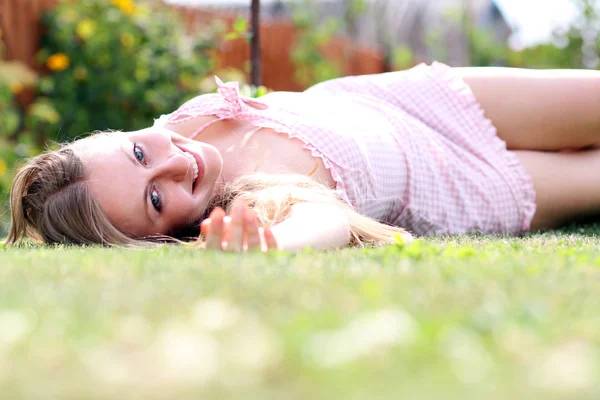 Ung kvinna liggande på gräsplan på park — Stockfoto