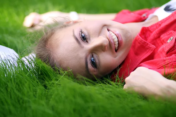 Bonito jovem mulher deitada no campo de grama no parque — Fotografia de Stock