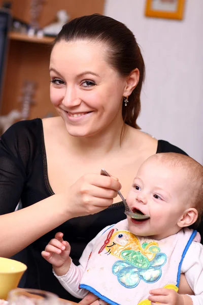 Mama spoon-feeds het kind — Stockfoto