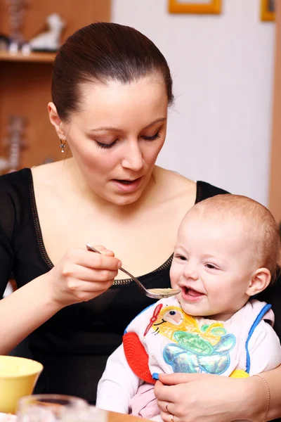 Mama spoon-feeds het kind — Stockfoto