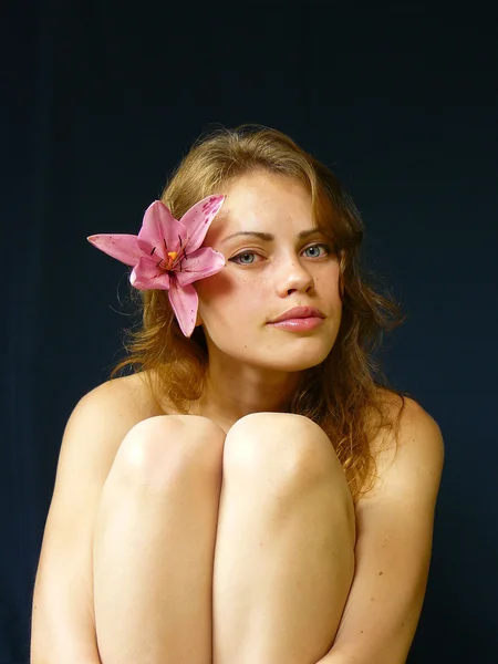 Girl with a lily in hairs — Stock Photo, Image
