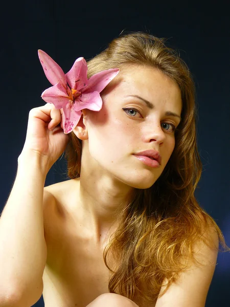 Woman with a lily in hairs — Stock Photo, Image