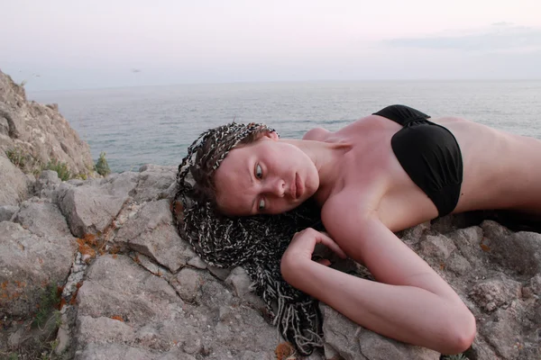 女孩躺在海边的石头上 — 图库照片