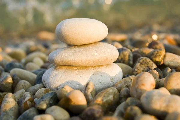 Três rochas equilibradas contrastam um mar de pedras — Fotografia de Stock